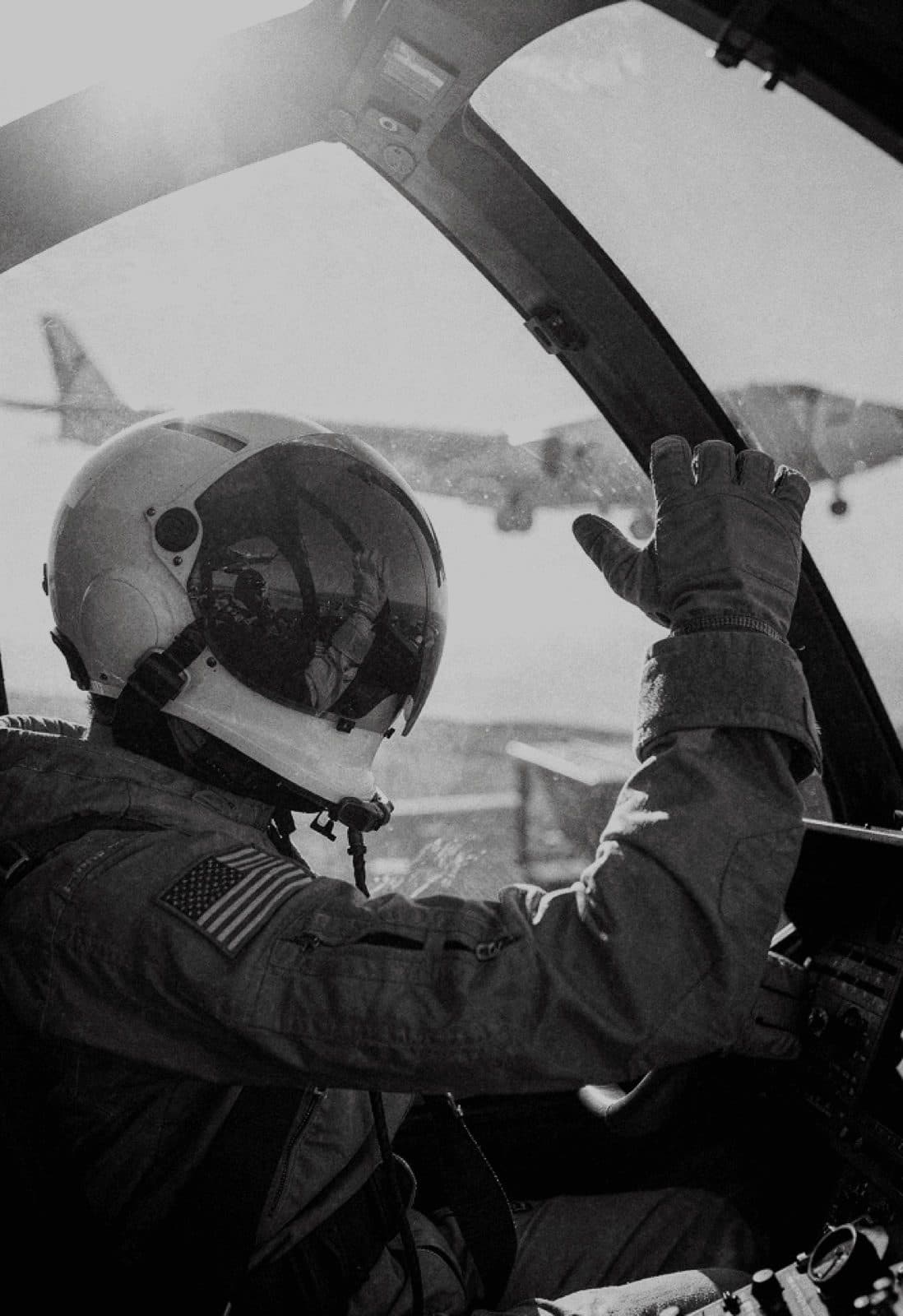 Pilot saluting a wingman from the cockpit